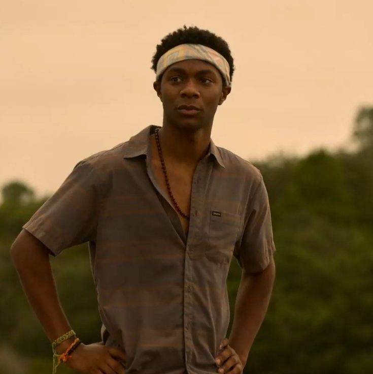 a man standing with his hands on his hips wearing a headband and looking at the camera