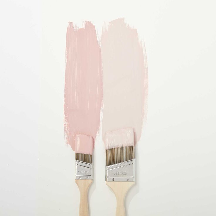 two pink paint brushes with white bristles on top of each other, against a white background