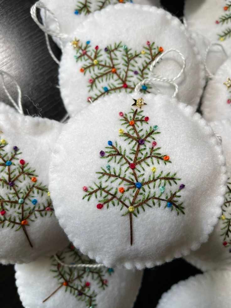 several white ornaments with embroidered trees on them