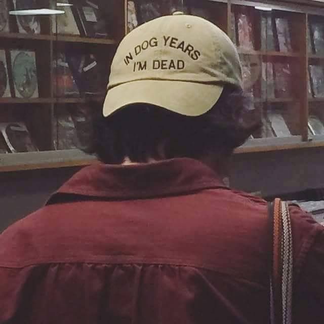 a man wearing a hat that says, my dog years i'm gay on it