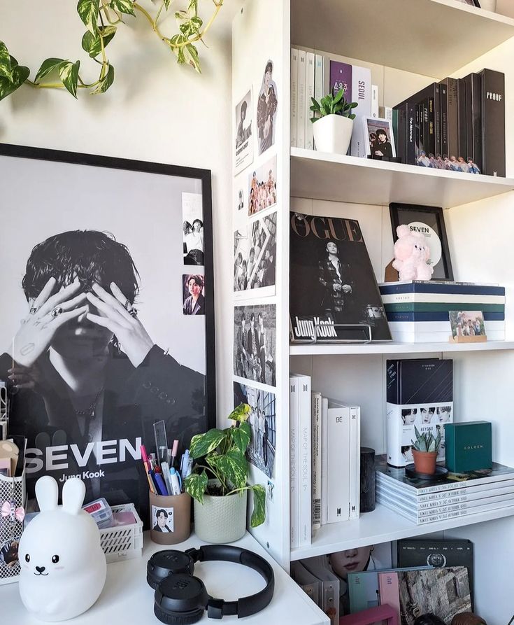 a white desk topped with lots of books next to a shelf filled with plants and other items