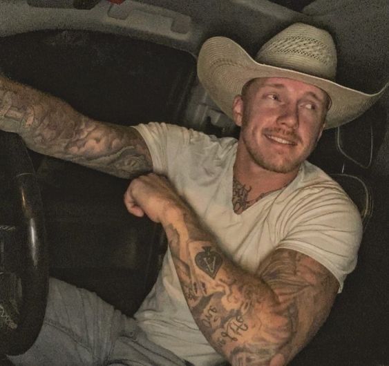 a man wearing a cowboy hat sitting in the driver's seat of a car