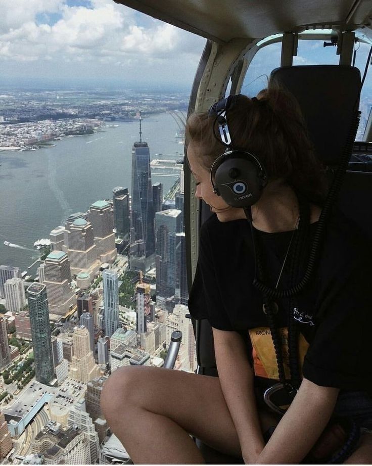 a woman sitting on top of a tall building with headphones in front of her