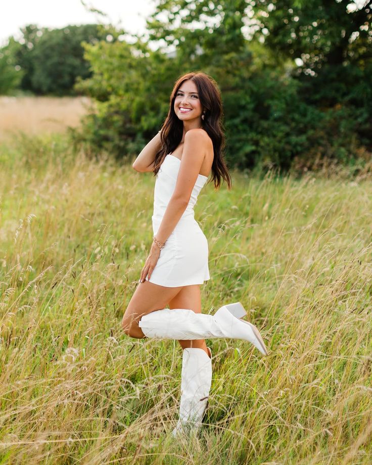 a beautiful young woman posing for a photo in tall grass with her legs spread out