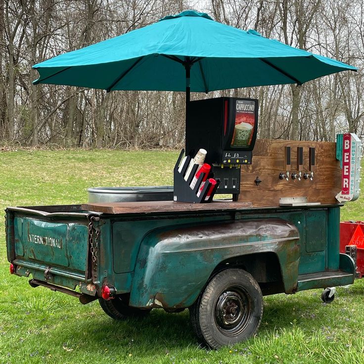 an old green truck with a blue umbrella over it