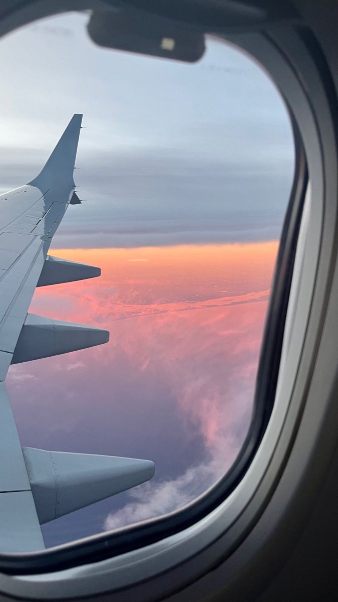 the wing of an airplane as it flies above the clouds at sunset or dawn in the sky