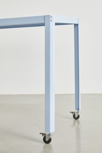 a blue table sitting on top of a white floor next to a metal frame with wheels