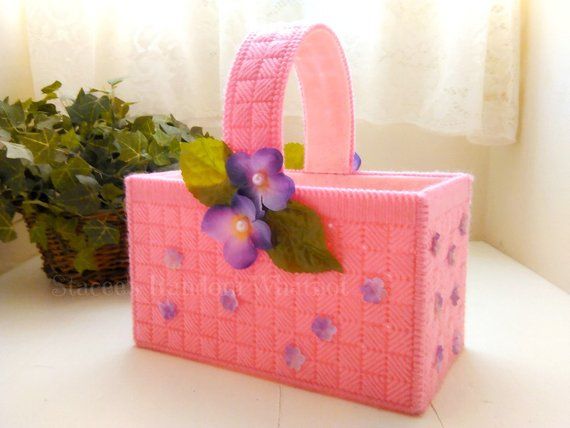 a pink purse with purple flowers on the handle and green leaves sticking out of it