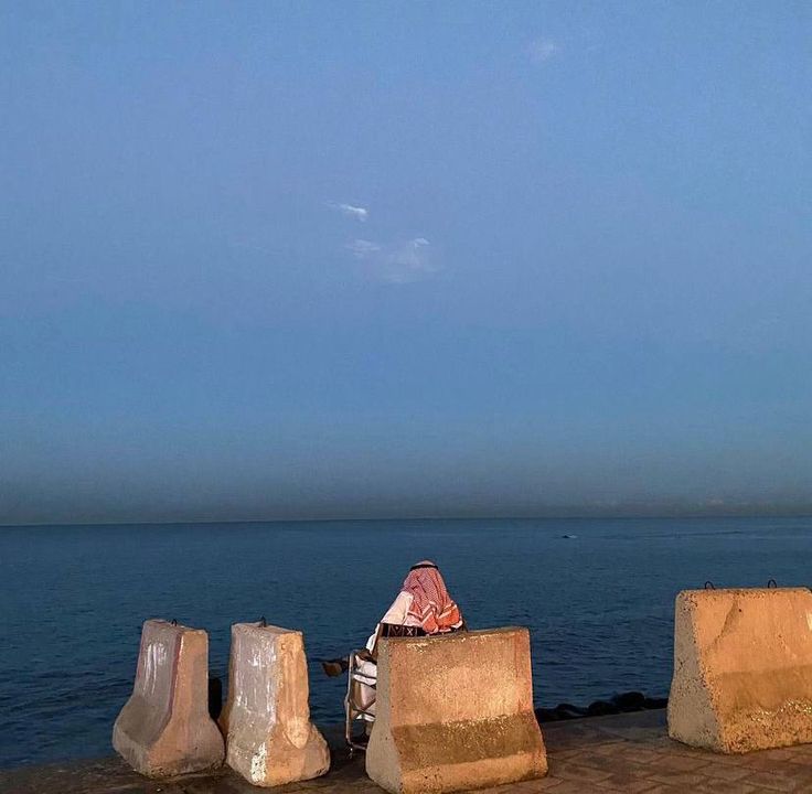 there is a person sitting on some rocks by the water