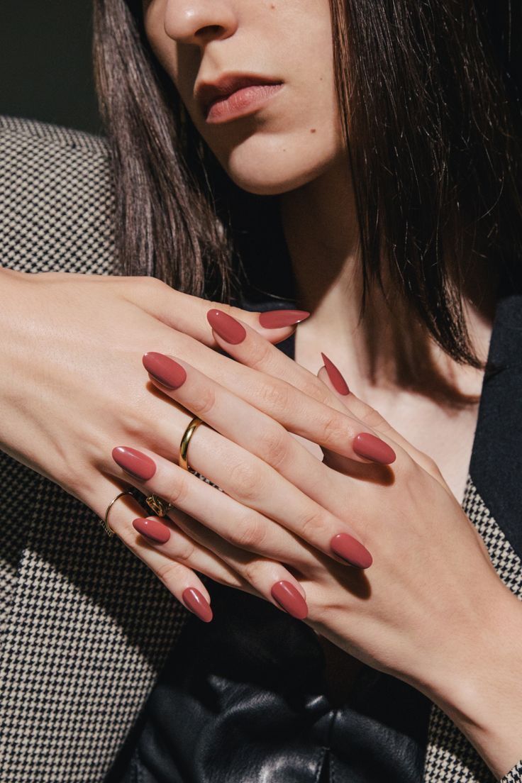 a woman with red nail polish holding her hand on her chest and wearing a ring