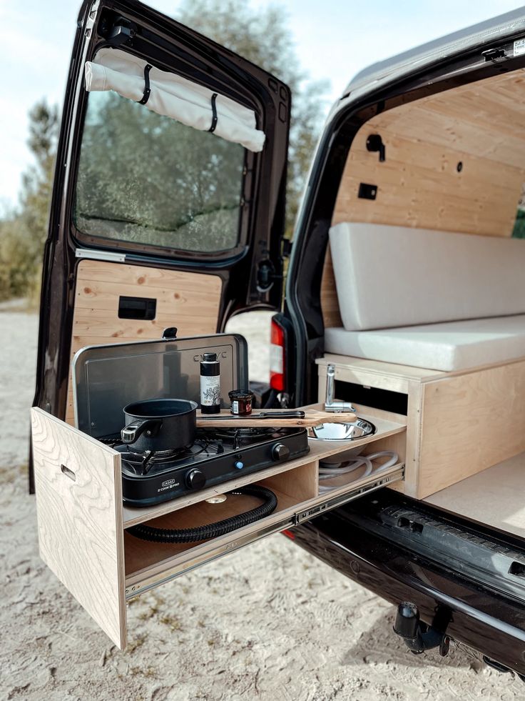 an open camper van with its door open and the back doors opened to show it's interior