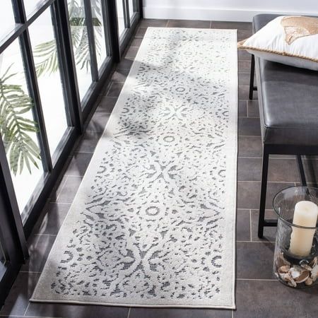 a white rug with an intricate design on the floor next to two chairs and a candle