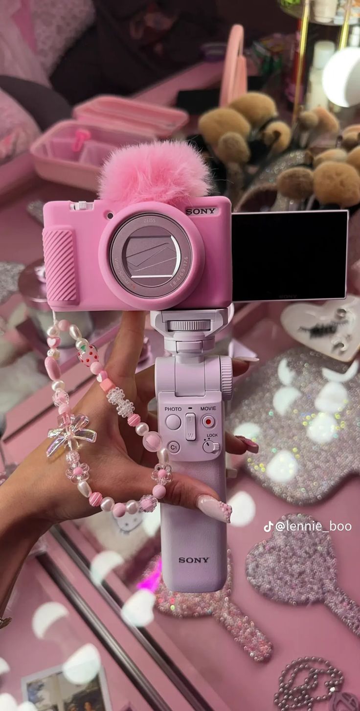 a pink camera is being held up in front of a mirror with other items on it