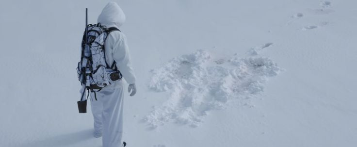 a person standing in the snow with a backpack on his back and skis attached to their shoulders