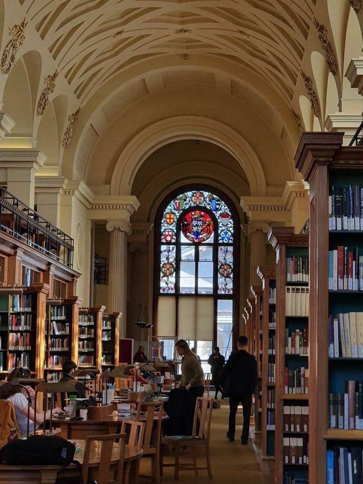 the inside of a library with many bookshelves and people sitting at tables in front of them