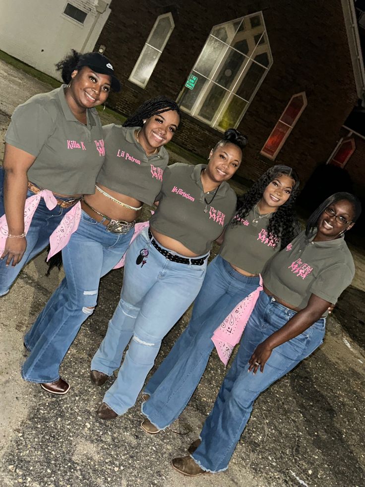 a group of women standing next to each other in front of a brick building at night