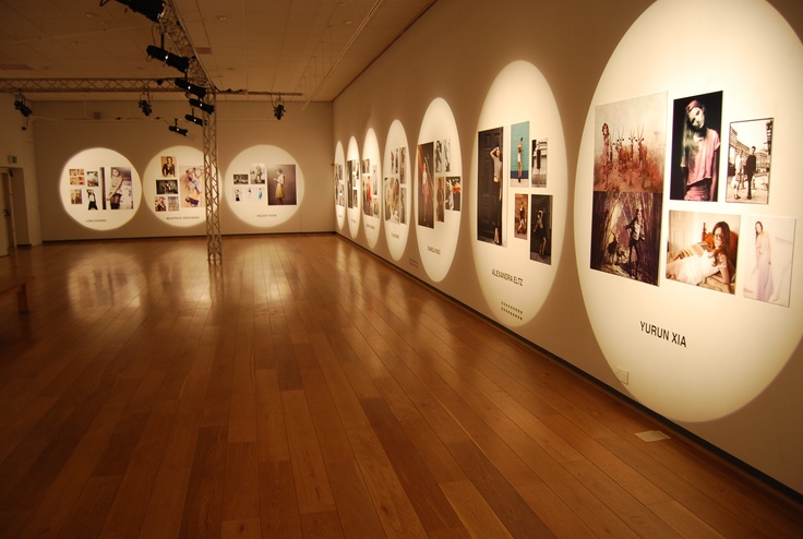 an empty room with many pictures on the wall and wooden floors in front of it