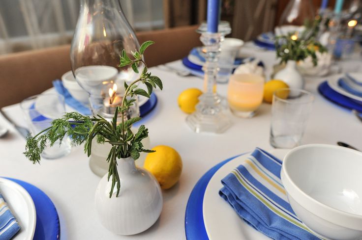 the table is set with blue and white plates, silverware, and lemons