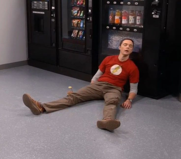 a man laying on the floor in front of a vending machine