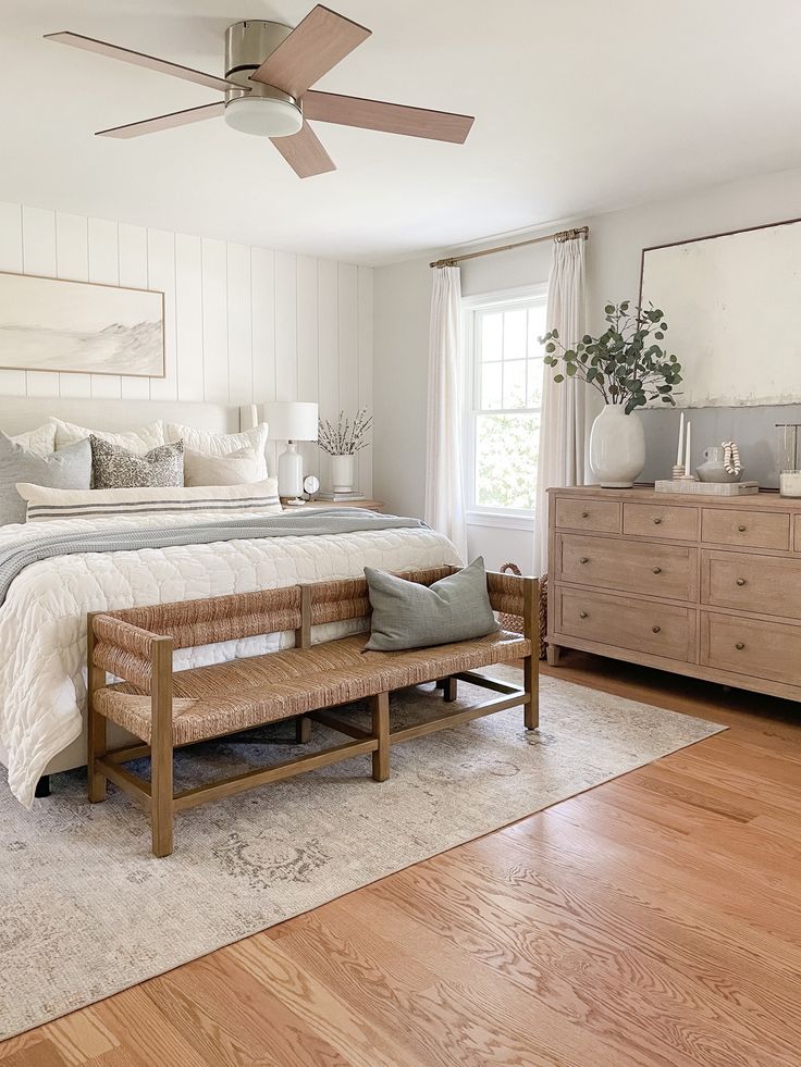 a bed room with a neatly made bed and a wooden bench next to a window