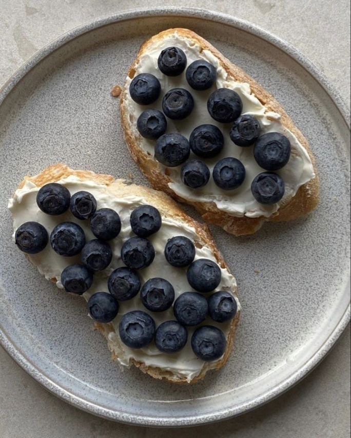 two pieces of bread with blueberries on them are sitting on a plate next to each other