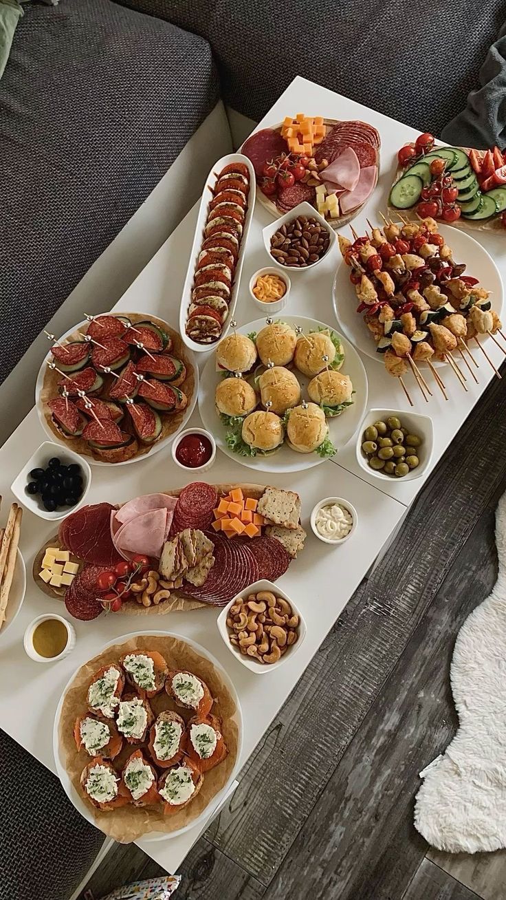 a table filled with food and snacks on top of a wooden floor next to a couch