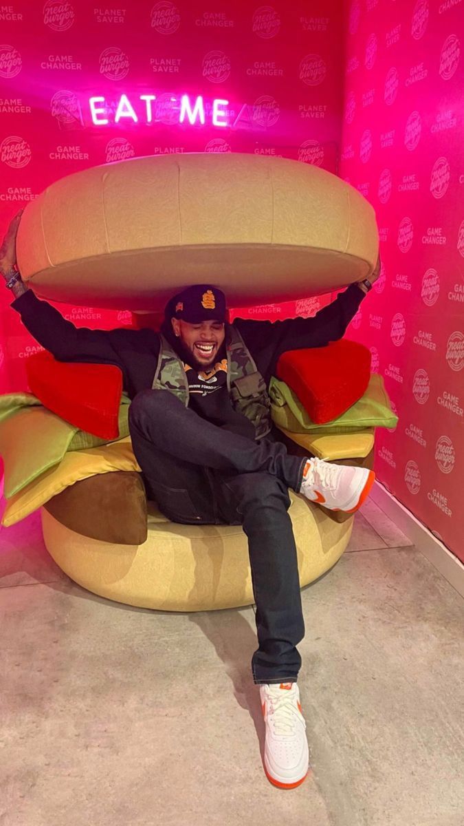 a man sitting in a giant hamburger chair