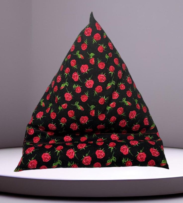 a black and red hat with roses on it sitting on top of a white table