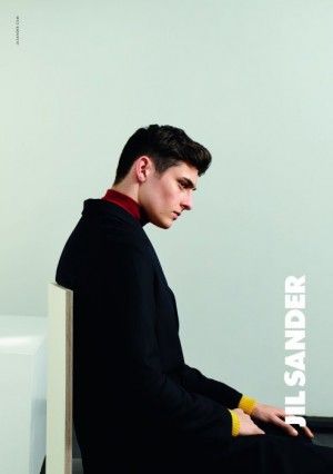 a young man sitting on top of a white chair in front of a black and white wall