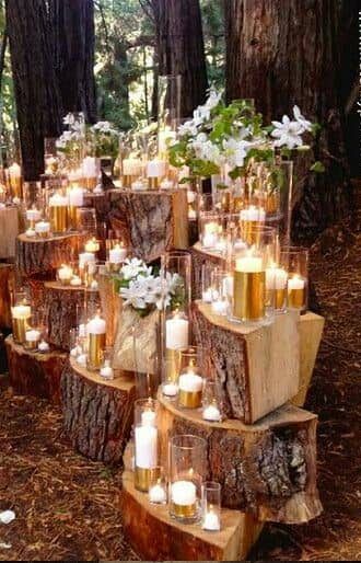 many candles are placed in glass vases on logs