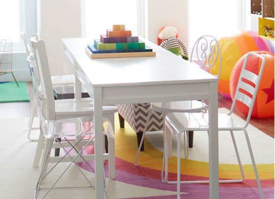 a white table and chairs in a room with bright colored rugs on the floor