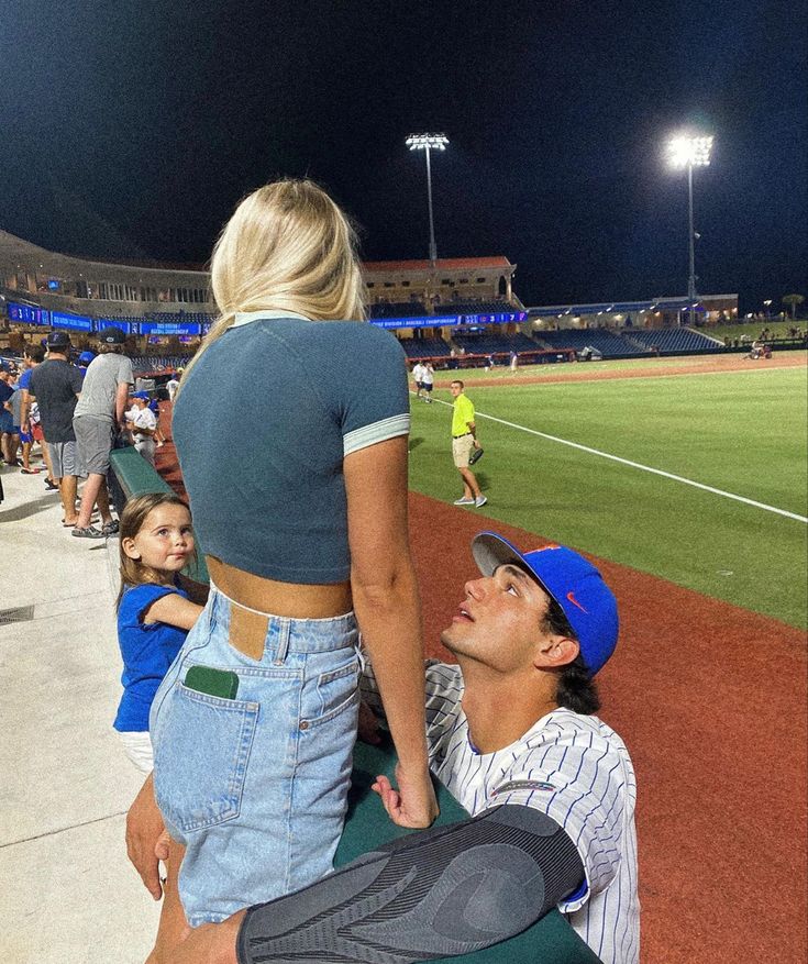 a man and woman sitting on a bench at a baseball game