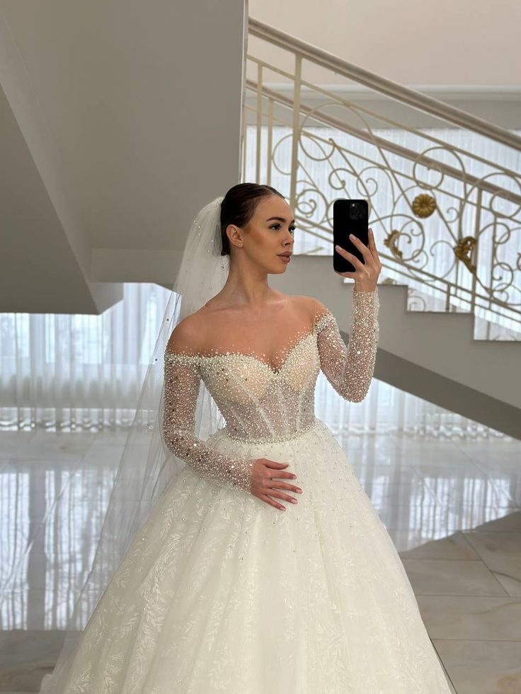 a woman in a wedding dress taking a selfie with her cell phone while wearing a veil