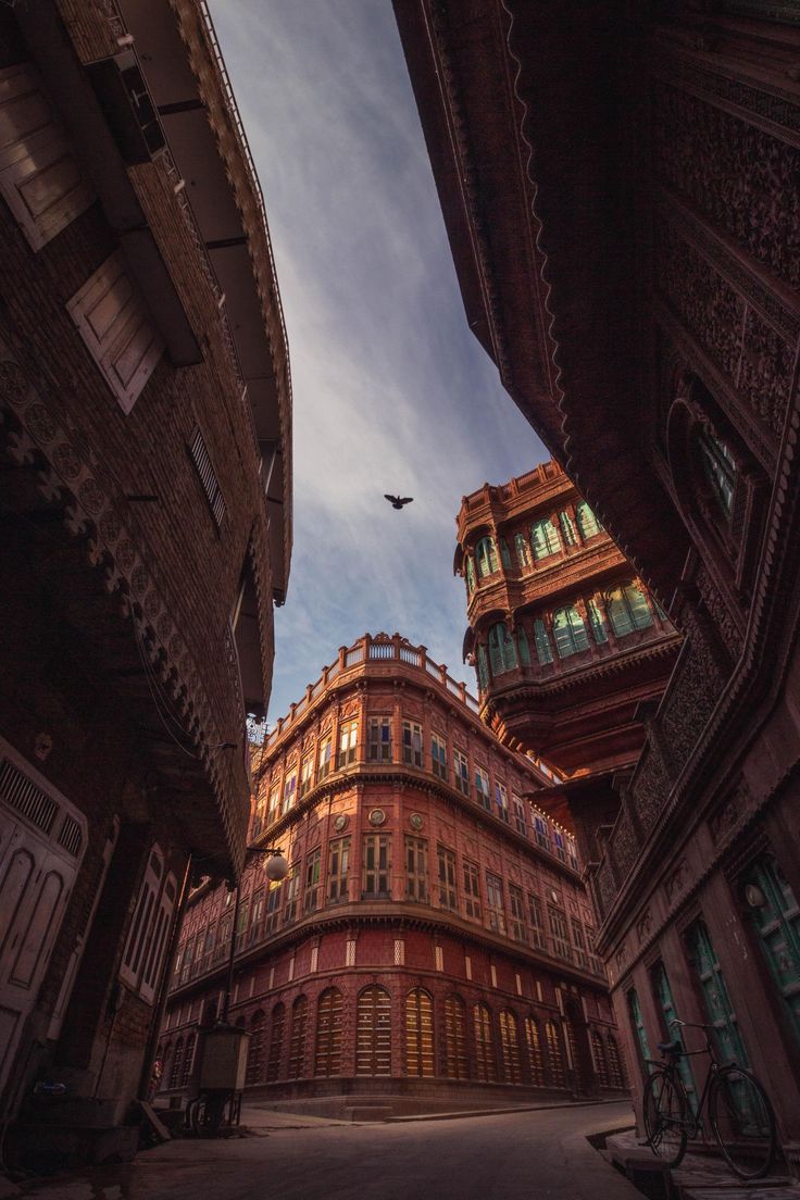 an alley way with buildings and birds flying in the sky