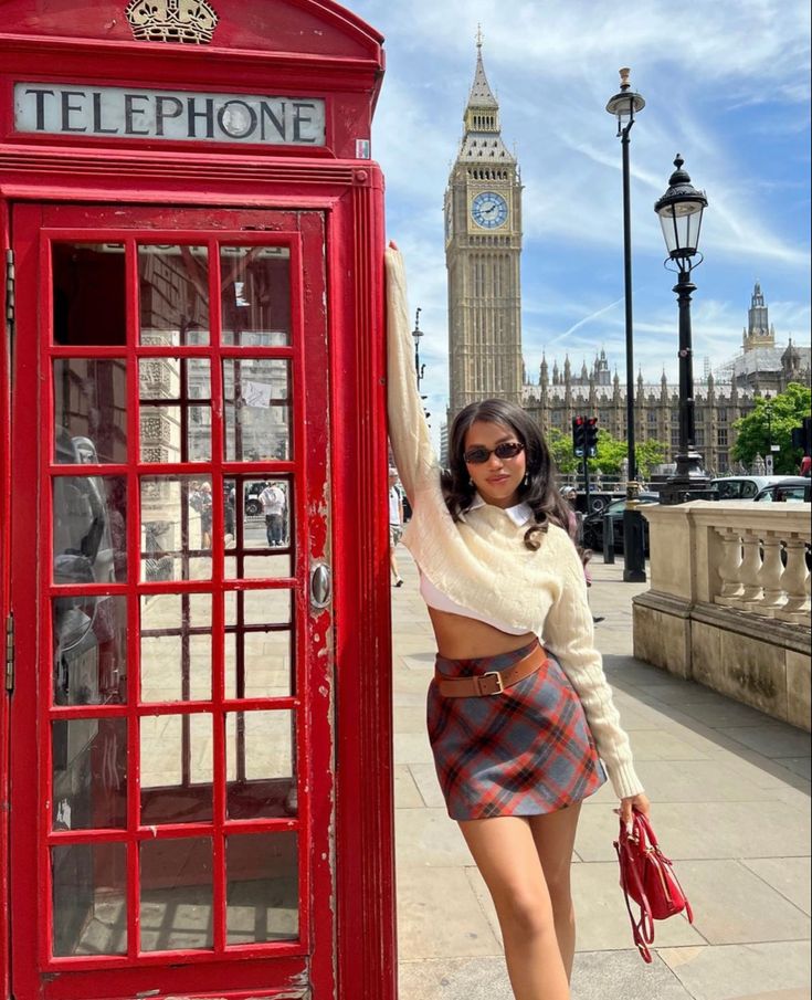 a woman standing next to a red phone booth