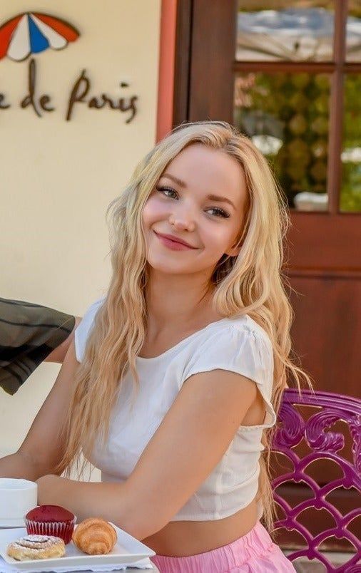 a woman sitting at a table with a cup of coffee and donut in front of her