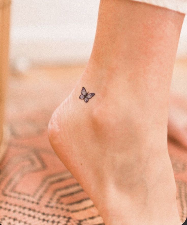 a woman's foot with a small butterfly tattoo on her left ankle and right leg