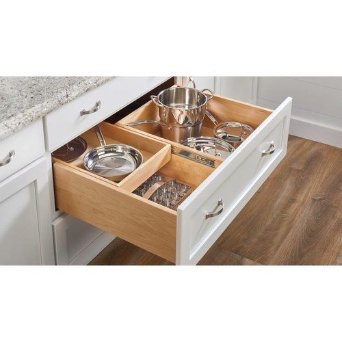 an open drawer in a kitchen with pots and pans on the bottom shelf,