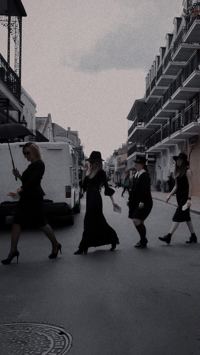 four women walking down the street with umbrellas in hand and one holding an umbrella