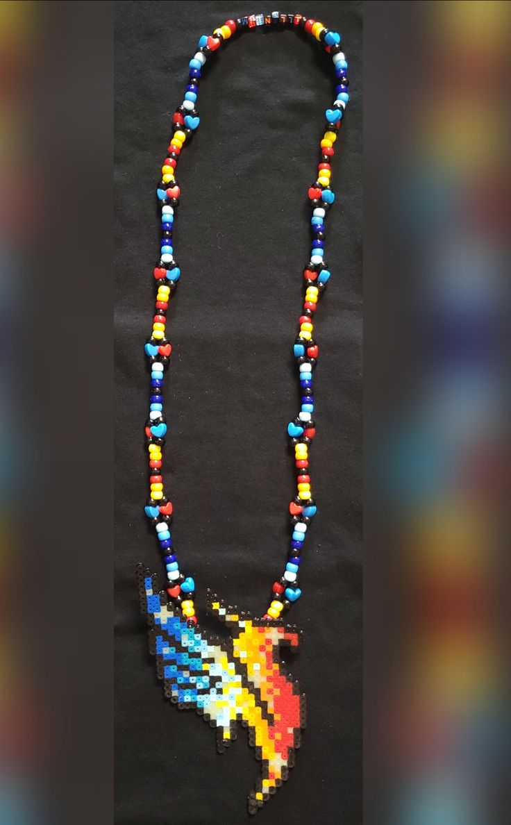 a multicolored beaded necklace with a bird on it's end and a black background