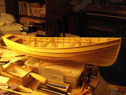 a wooden boat sitting on top of a table next to other tools and supplies in boxes