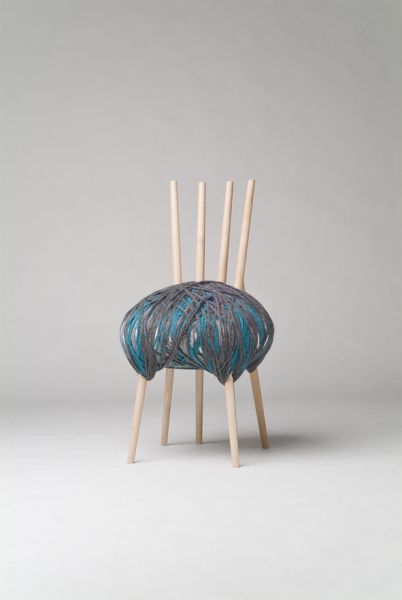 a chair made out of wood sticks with blue paint on the back and arms, sitting in front of a gray background