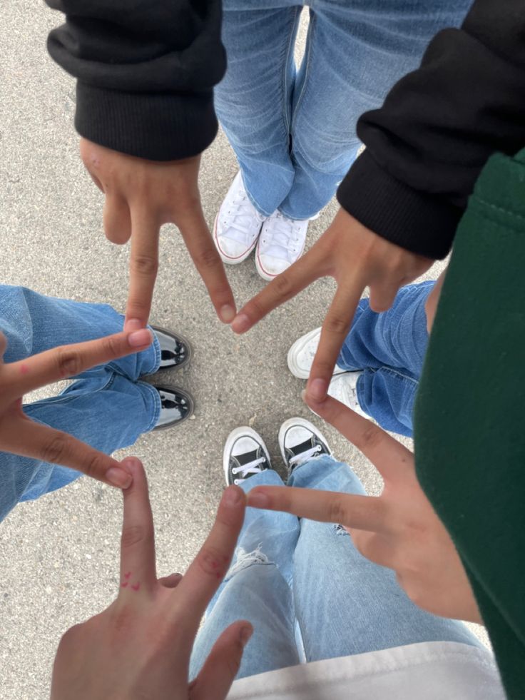 four people standing in a circle making the shape of a star with their hands together