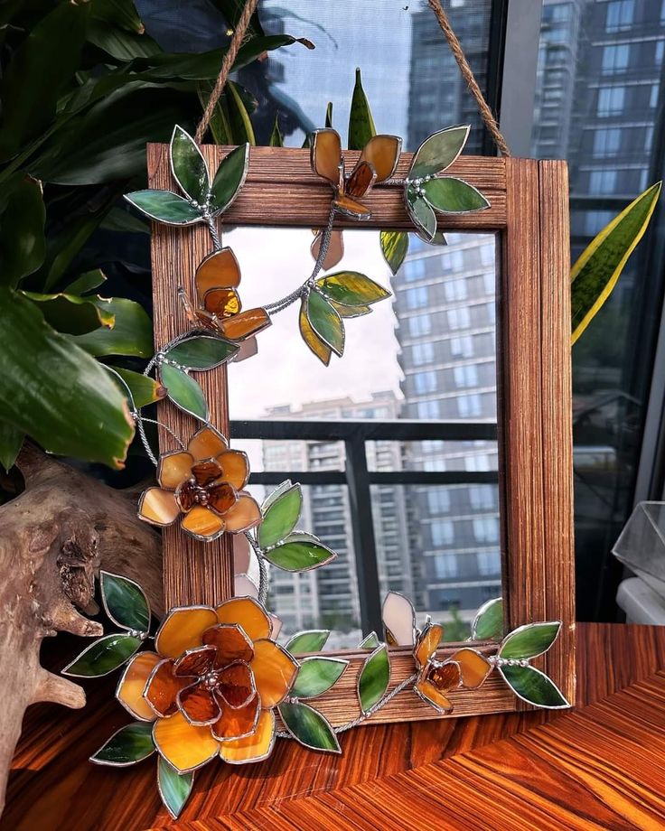 a wooden frame with glass flowers hanging from it's sides on a table in front of a window