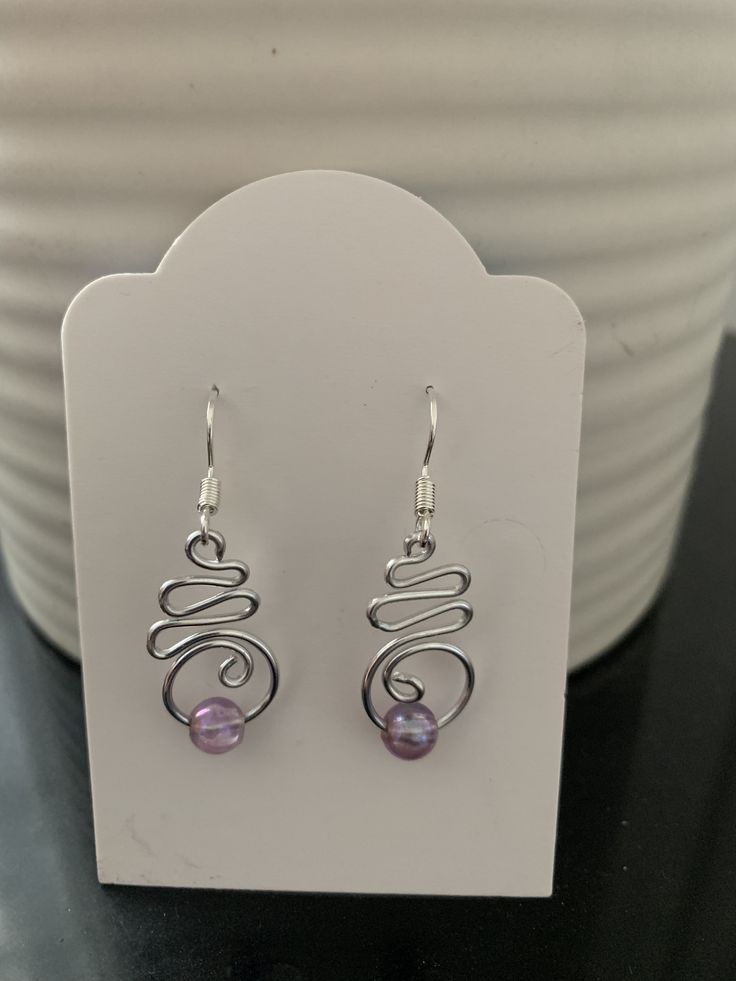 the earrings are on display in front of a white bowl with a black table top