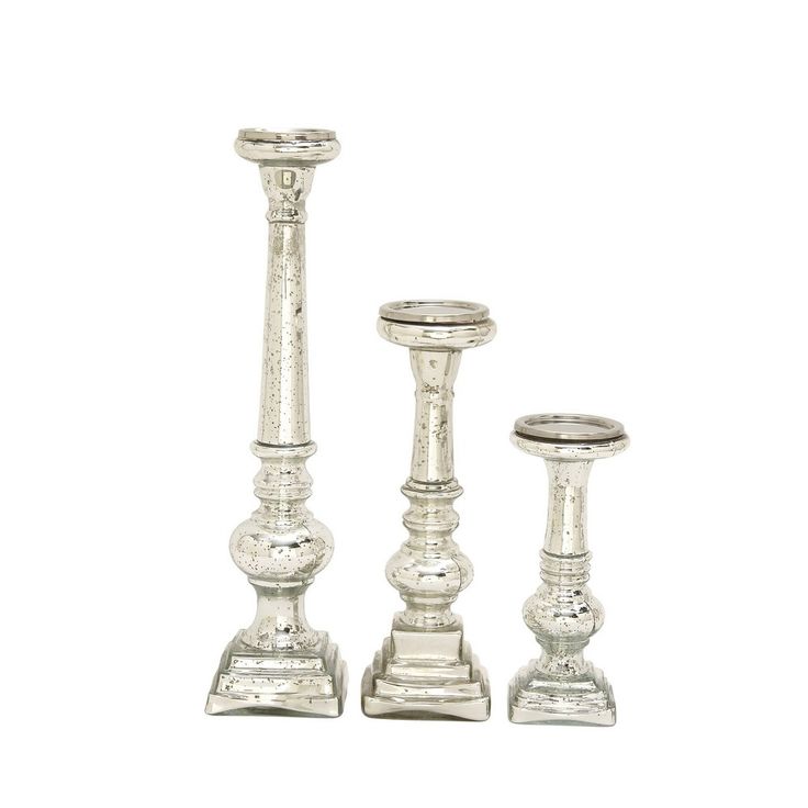 three silver candlesticks sitting next to each other on top of a white surface