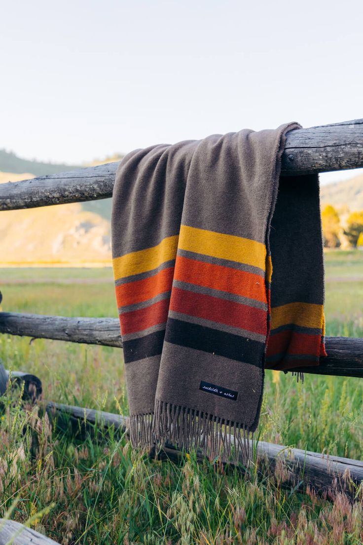 a blanket hanging on a wooden fence in the grass