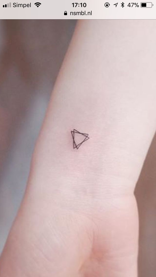 a small triangle tattoo on the wrist is shown in black ink, and it looks like an arrow