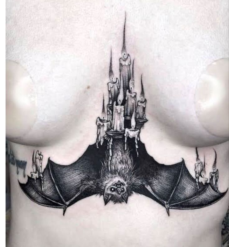 a black and white photo of a bat tattoo on the side of a woman's chest