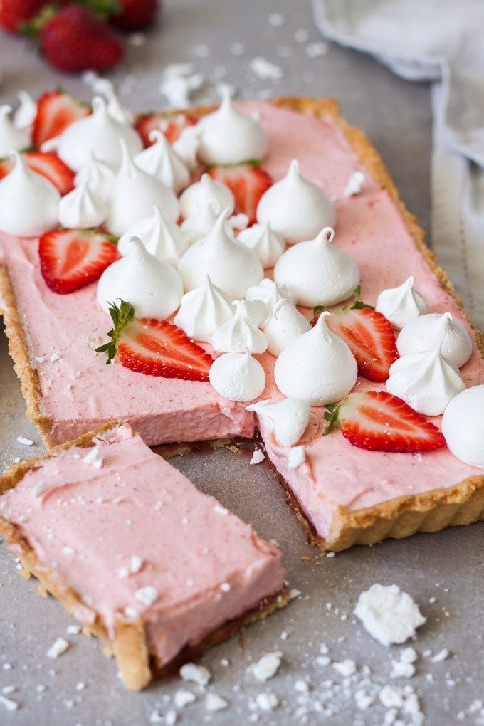 a piece of pie with whipped cream and strawberries on top is sitting on a table